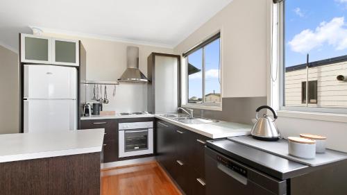 a kitchen with white appliances and a large window at Shore Thing Upstairs - Coastal Family Retreat in Lake Tyers
