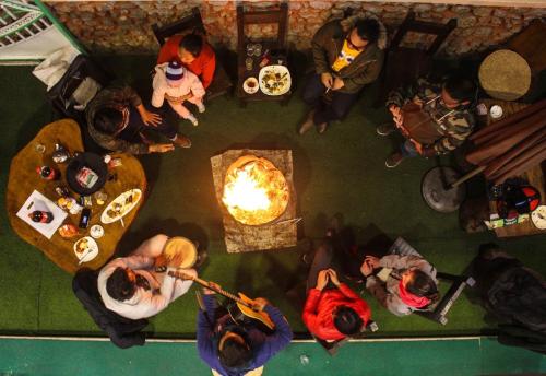 un grupo de personas sentadas alrededor de una mesa con fuego en Mingo Guest House, en Pokhara