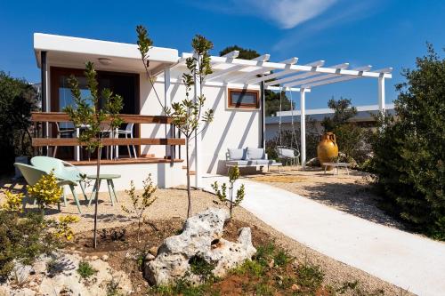 a white house with a pergola in a yard at Macchia Piccinna in Maruggio