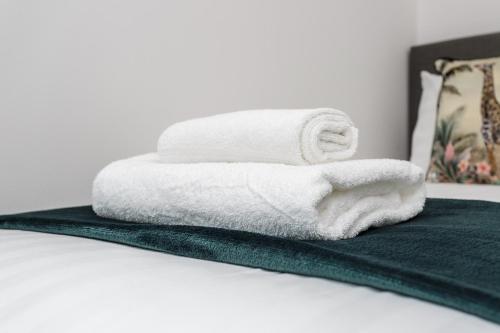 a stack of towels sitting on top of a bed at Milton Heights - Modern 2 bedroom apartment with terrace in Portsmouth in Portsmouth