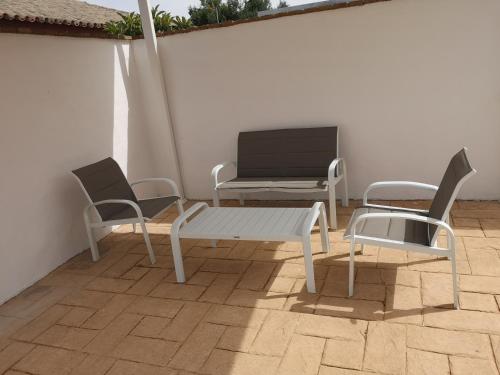 patio z 2 krzesłami, stołem i telewizorem w obiekcie Casa Alma w mieście Conil de la Frontera