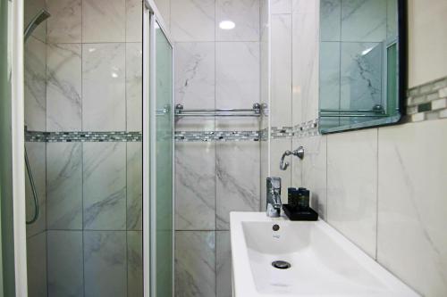 bagno con doccia, lavandino e specchio di Phaedrus Living: Seaside Luxury Flat Lighthouse 66 a Paphos