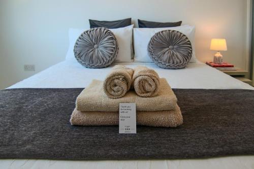 a bed with a pile of towels on it at Phaedrus Living: Seaside Luxury Flat Lighthouse 66 in Paphos