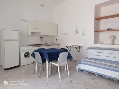 a kitchen with a blue table and chairs and a bed at Corte nel borgo in Minervino di Lecce