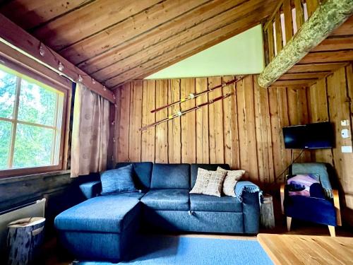 sala de estar con sofá azul en una habitación con paredes de madera en Lapland Tunturimaja Ski in, sauna, in Pyhä center - Lapland Villas en Pyhätunturi