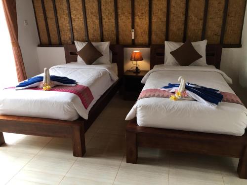 um quarto com 2 camas e toalhas em Bale Lumbung Bungalows em Nusa Penida
