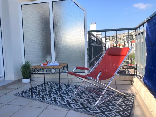un fauteuil rouge et une table sur un balcon dans l'établissement Appartement Terrasse Quartier Liberation, à Nice