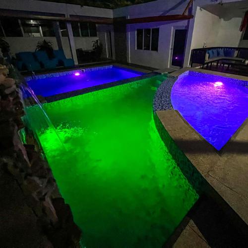 a swimming pool with green water and purple lights at Casa Cecilia Hotel in Bantay