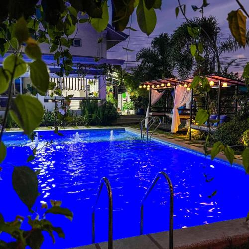 a swimming pool lit up in blue at night at Casa Cecilia Hotel in Bantay