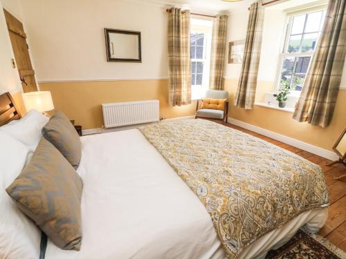 a large white bed in a room with windows at Tiplady Cottage in Leyburn