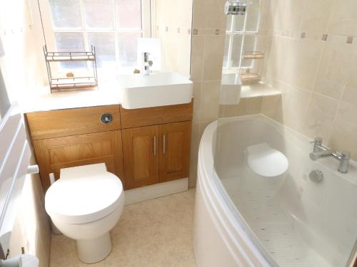 a bathroom with a toilet and a tub and a sink at Tiplady Cottage in Leyburn