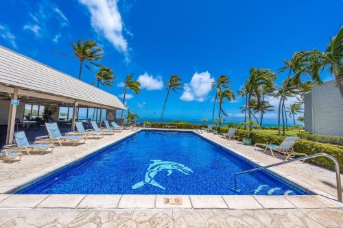 a swimming pool with chairs and palm trees at Wavecrest in Kaunakakai