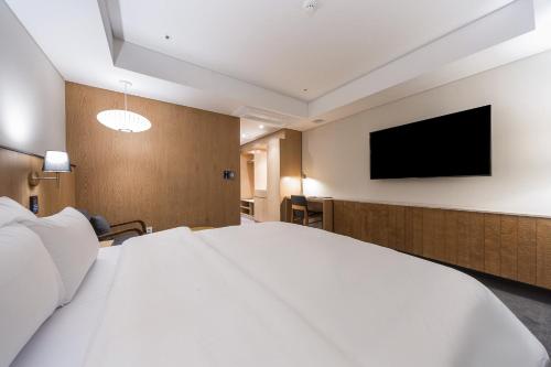 a hotel room with a large white bed and a flat screen tv at Gwangju HOUND Hotel in Gwangju