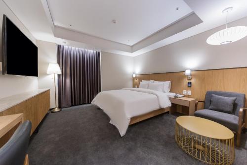 a hotel room with a bed and a tv and a chair at Gwangju HOUND Hotel in Gwangju