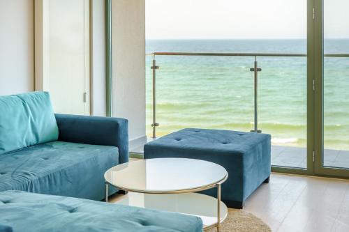 a living room with a blue couch and a table at Apartamenty Na Klifie in Ustronie Morskie