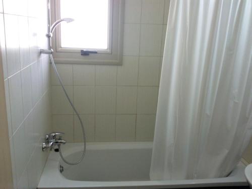 a bathroom with a tub and a shower curtain at Bowker Apartment in Protaras
