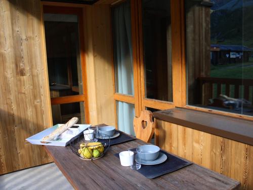 - une table en bois avec un bol de fruits sur une terrasse couverte dans l'établissement Studio rénové 2019 · Ski aux pieds · Balcon · 4 pers - FR-1-181-1997, à La Plagne Tarentaise
