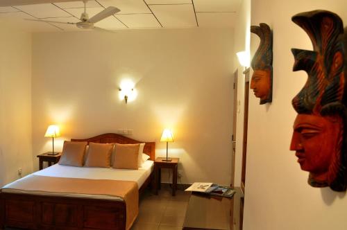 - une chambre avec un lit et deux lampes murales dans l'établissement Ayubowan Guesthouse, à Negombo