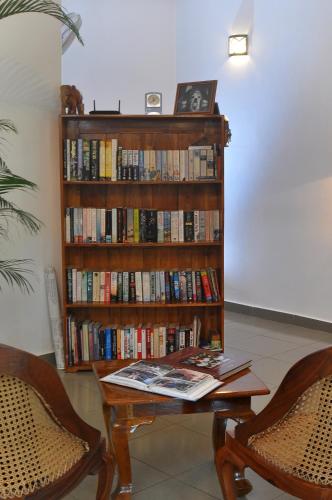 a book shelf full of books with a table and chairs at Ayubowan Guesthouse in Negombo
