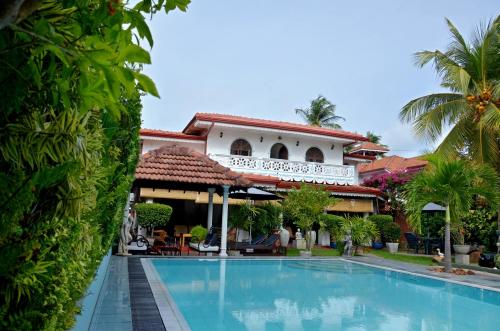 a swimming pool in front of a house at Ayubowan Guesthouse in Negombo