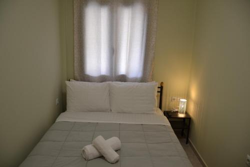 un letto con due asciugamani sopra con una finestra di Frygano Apartments 1 a Oitylo