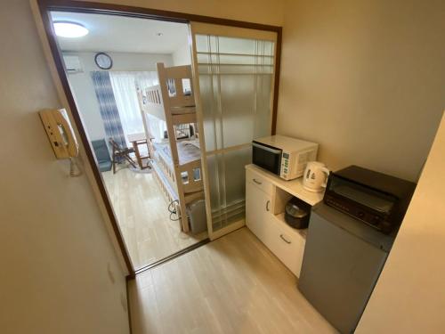 a small room with a microwave and a kitchen at ローズパーク弐番館 in Funabashi