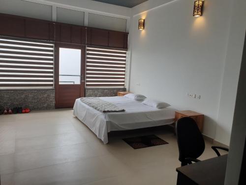 a bedroom with a bed and a desk and windows at Seekend Holidays Munnar in Chinnakanal