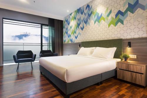 - une chambre avec un grand lit et une chaise dans l'établissement Le Vert Boutique Hotel, à Genting Highlands