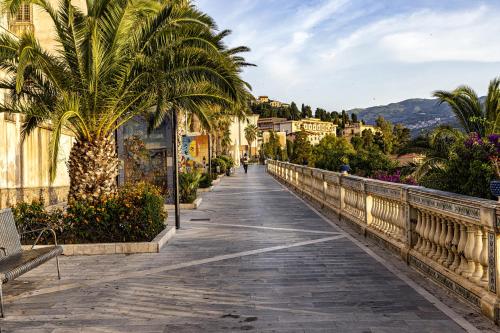 a bridge over a river with palm trees and buildings at La dimora dei ricci in Santo Stefano di Camastra