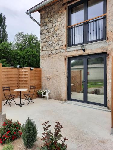 a patio with a table and chairs next to a building at Le Petit Bégou in Saint-Auban-dʼOze