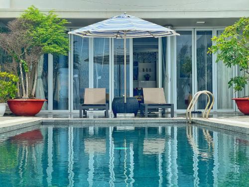 una piscina con 2 sillas y una sombrilla junto a una casa en Oceanami 5 Bedrooms Private Pool, en Long Hai