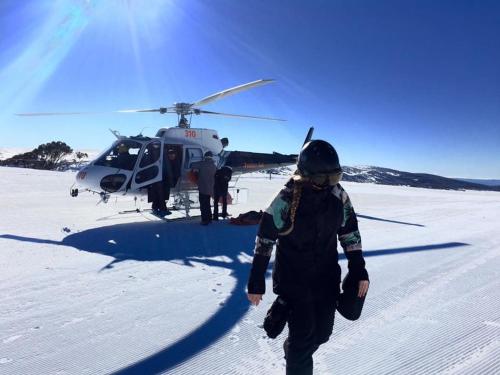 a woman walking towards a helicopter in the snow at Harrietville Hotel Motel in Harrietville
