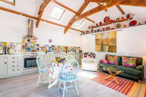 a kitchen and living room with a couch and chairs at Polrunny Farm Sloe Cottage with a sea view in Boscastle