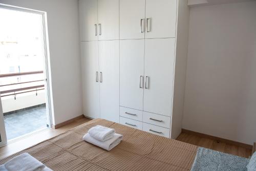 a white bedroom with white cabinets and a bed at Renovated apartment 5min from subway station 'Attiki' in Athens