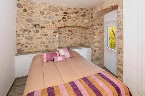 赫羅納的住宿－Apartamento histórico en el Barri Vell Girona，一间卧室配有一张带粉色和紫色枕头的床
