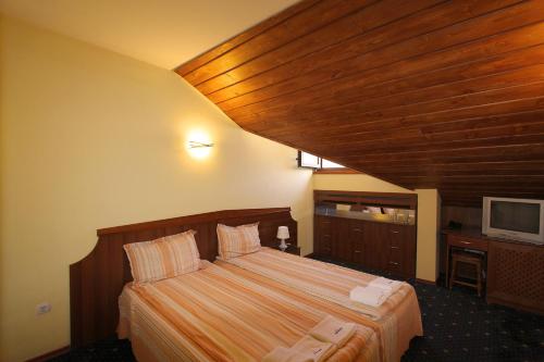 a bedroom with a large bed with a wooden ceiling at Kap House Family Hotel in Bansko