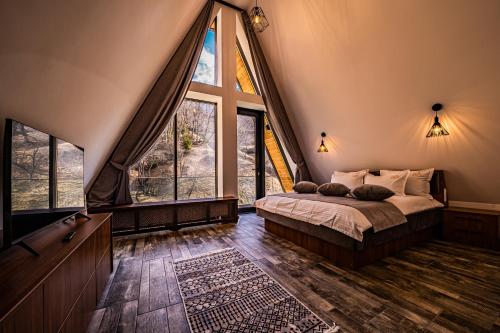 a bedroom with a bed in a room with large windows at CABANELE IULI'S HOME in Runcu