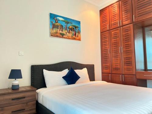 a bedroom with a white bed and a wooden cabinet at Fairview Luxury Apartments in Dar es Salaam