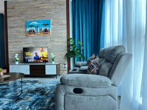 a living room with a chair and a television at Fairview Luxury Apartments in Dar es Salaam