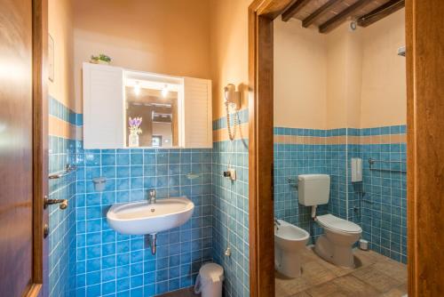 uma casa de banho em azulejos azuis com um lavatório e um WC em Poggio Primo - Monolocale Saraceno em Castiglion Fibocchi