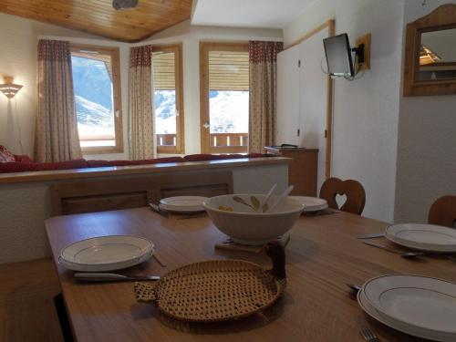 une table de salle à manger avec des assiettes et un bol dessus dans l'établissement Appartement skis aux pieds avec balcon - FR-1-181-2035, à La Plagne Tarentaise