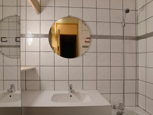 La salle de bains est pourvue de carrelage blanc, d'un lavabo et d'un miroir. dans l'établissement Studio divisible au cœur de la station avec balcon, animaux admis - FR-1-181-2095, à La Plagne Tarentaise