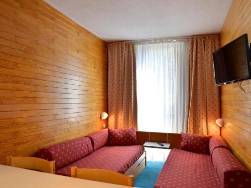 une chambre d'hôtel avec un canapé et une télévision dans l'établissement Studio divisible au cœur de la station avec balcon, animaux admis - FR-1-181-2095, à La Plagne Tarentaise
