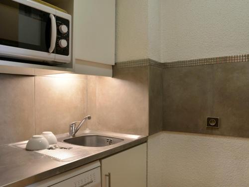une cuisine avec un évier et un micro-ondes dans l'établissement Studio divisible au cœur de la station avec balcon, animaux admis - FR-1-181-2095, à La Plagne Tarentaise