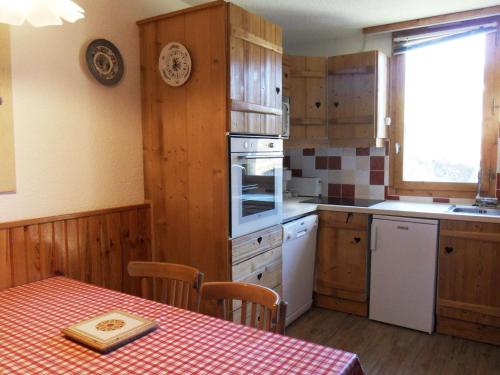 une cuisine avec des placards en bois et une table avec un chiffon de table dans l'établissement Appartement chaleureux 5 pers, accès pistes, balcon, WIFI, animaux admis - FR-1-181-2098, à La Plagne Tarentaise