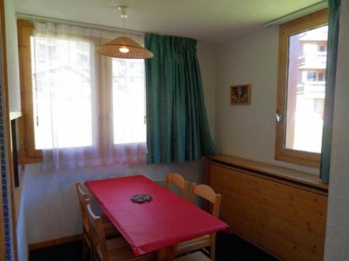 une salle à manger avec une table et des chaises rouges dans l'établissement Appartement tout confort, accès direct aux pistes, balcon, casier à ski - FR-1-181-2152, à La Plagne Tarentaise