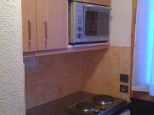 une cuisine avec une cuisinière et un micro-ondes dans l'établissement Appartement tout confort, accès direct aux pistes, balcon, casier à ski - FR-1-181-2152, à La Plagne Tarentaise