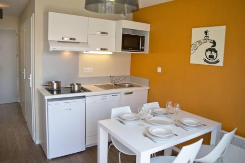 a kitchen with a white table and white chairs at Résidence Les Rives de la Fecht - Colmar Ouest in Ingersheim