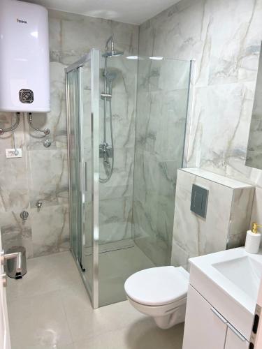 uma casa de banho com um chuveiro, um WC e um lavatório. em Apartman Laura em Mlini