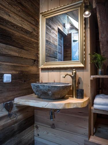 une salle de bain avec un lavabo en pierre et un miroir dans l'établissement Venez Chez Vous - Chalet Le Banc du cerf, à Rovagny